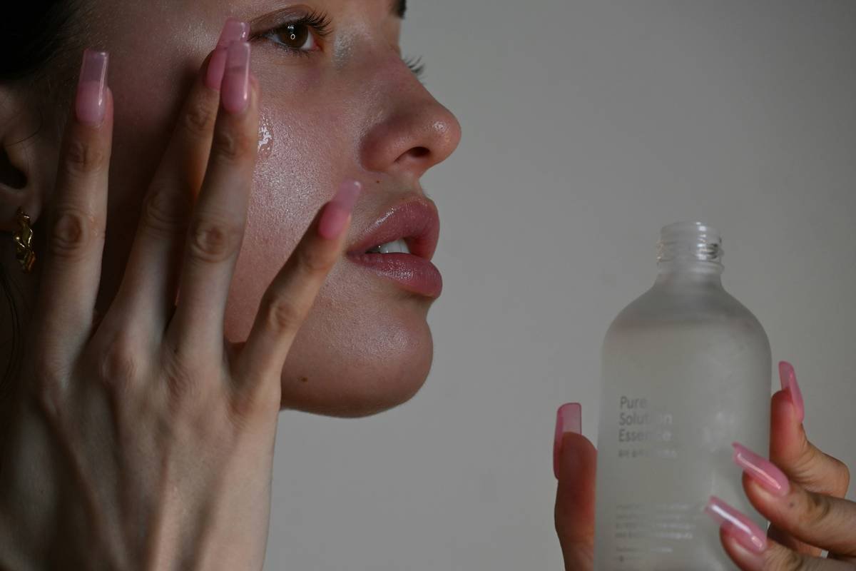Woman applying rich moisturizing balm face to dry cheeks with fingertips